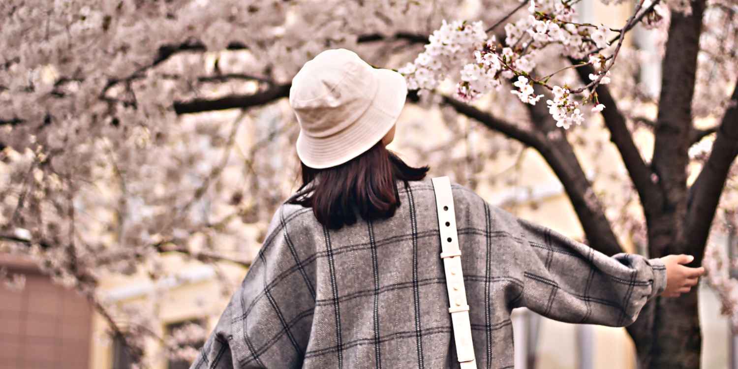 Une femme porte un bob sous des arbres.