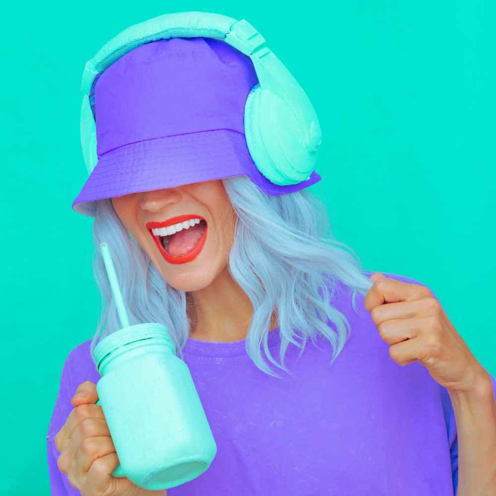 Une femme portant un bob, chante la musique dans son casque.
