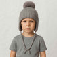 Un garçon porte le Bonnet Cache Oreille Gris à Pompon pour Enfant 