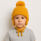 Un garçon porte le Bonnet Cache Oreille Jaune à Pompon pour Enfant 